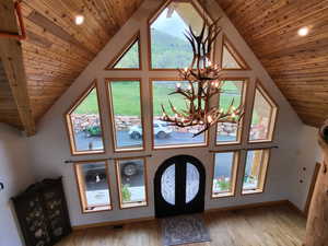 Foyer entrance with a chandelier, vaulted ceiling, wood ceiling, light wood finished floors, and french doors