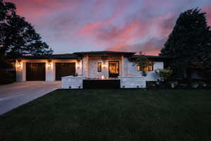 View of front of house with concrete driveway, a lawn, a garage, and stone siding