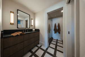 Full bath with vanity, inlaid floor details, a shower stall, and tile patterned floors