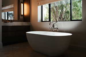 Full bath with healthy amount of natural light, vanity, and a freestanding tub