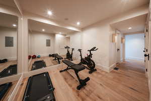 Workout area with light wood-style floors, recessed lighting, and electric panel
