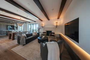 Living area with a fireplace, light wood-style flooring, and beamed ceiling