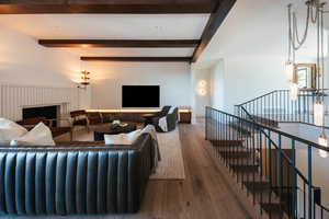 Living room with beamed ceiling, wood finished floors, and a fireplace