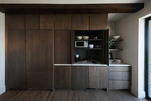 Bar featuring stainless steel microwave and wood finished floors