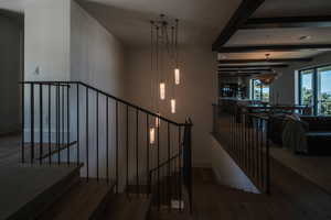 Stairway with wood finished floors and beam ceiling