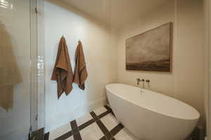 Full bathroom featuring a soaking tub, tile patterned flooring, tiled shower, and inlaid floor details