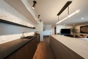 Kitchen with open floor plan, open shelves, dark brown cabinetry, dark countertops, and dark wood-type flooring
