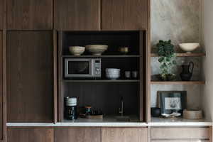 Kitchen view of stainless steel microwave, open shelves, modern cabinets, and dark brown cabinets