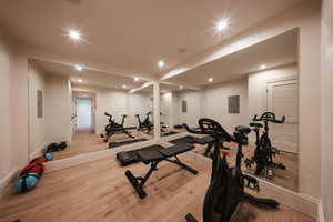 Workout room with recessed lighting, electric panel, and wood finished floors