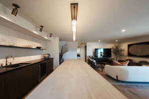 Kitchen with open floor plan, dark brown cabinetry, dark wood-style floors, open shelves, and recessed lighting