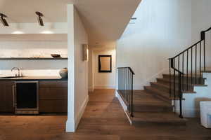 Indoor wet bar featuring wine cooler, dark wood finished floors, and stairway