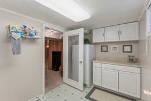 Kitchen featuring a textured ceiling, white cabinets, light countertops, and a heating unit