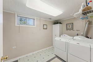 Laundry room featuring cabinet space, a textured ceiling, independent washer and dryer, and ornamental molding