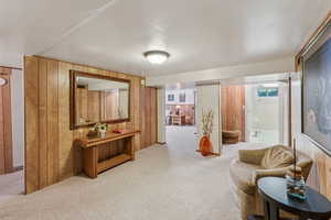 Carpeted living area featuring wooden walls