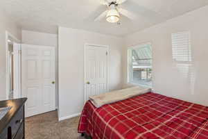 Carpeted bedroom with a textured ceiling and ceiling fan