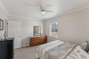 Bedroom with light colored carpet, ornamental molding, and ceiling fan