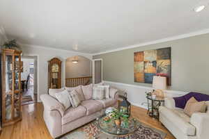 Living area with hardwood / wood-style floors, ornamental molding, and arched walkways