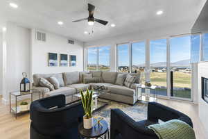 Living area with recessed lighting, light wood-style flooring, a textured ceiling, ceiling fan, and a mountain view