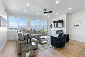 Living area featuring ceiling fan, baseboards, wood finished floors, a fireplace, and recessed lighting