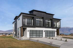 Modern home with a mountain view, a garage, a balcony, a front lawn, and concrete driveway