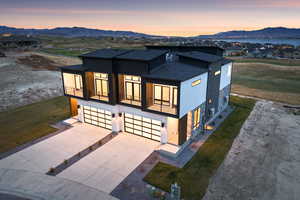 Contemporary house featuring a balcony, a mountain view, a shingled roof, an attached garage, and driveway