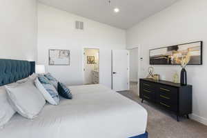 Bedroom with light colored carpet, high vaulted ceiling, ensuite bath, and recessed lighting