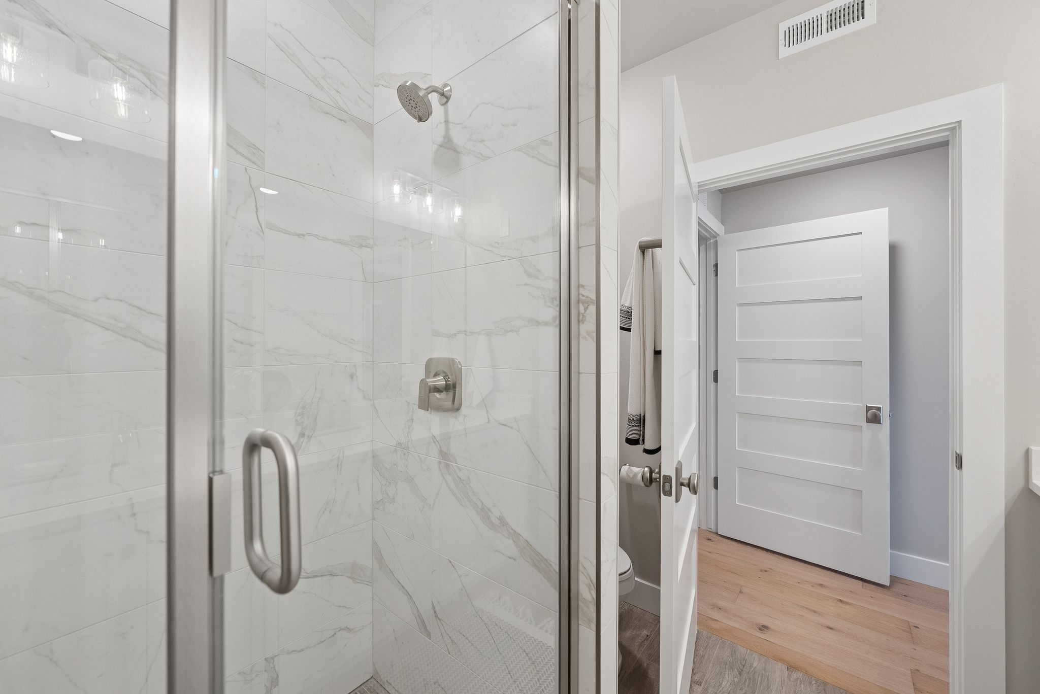 Full bathroom with wood finished floors and a marble finish shower