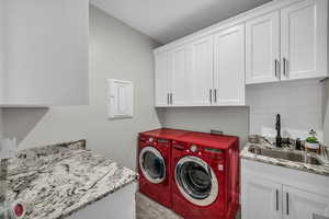 Washroom with cabinet space, washer and clothes dryer, and light wood finished floors