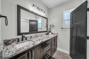Full bathroom with double vanity, plenty of natural light, and wood finished floors