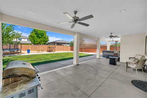 Fenced backyard featuring a trampoline, ceiling fan, a playground, a patio area, and a grill