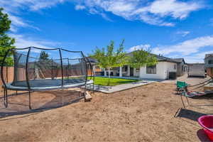 View of yard featuring a trampoline and a patio