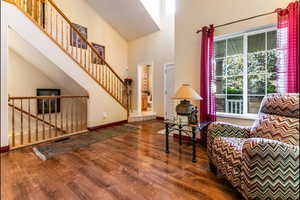 Living area with wood finished floors, a towering ceiling, and stairs