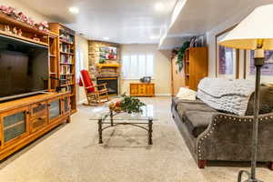 Basement carpeted living area featuring a stone fireplace and recessed lighting