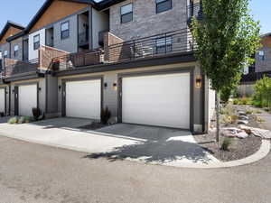 Multi unit property featuring a garage, a balcony, and driveway