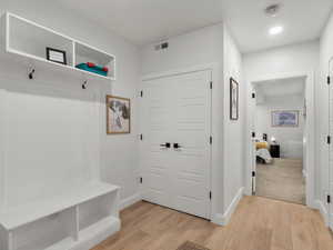 Mudroom with light wood finished floors and recessed lighting