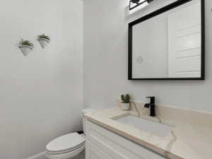 Half bathroom featuring vanity and toilet