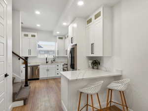 Kitchen with stainless steel appliances, a peninsula, recessed lighting, light stone counters, and a breakfast bar