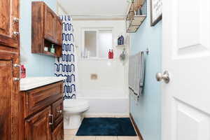 Full bath featuring tile patterned floors, vanity, and shower / tub combo with curtain