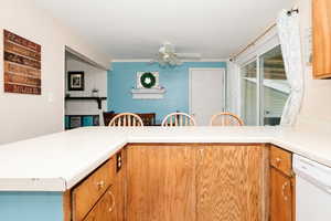 Kitchen featuring white dishwasher, ceiling fan, light countertops, and brown cabinetry