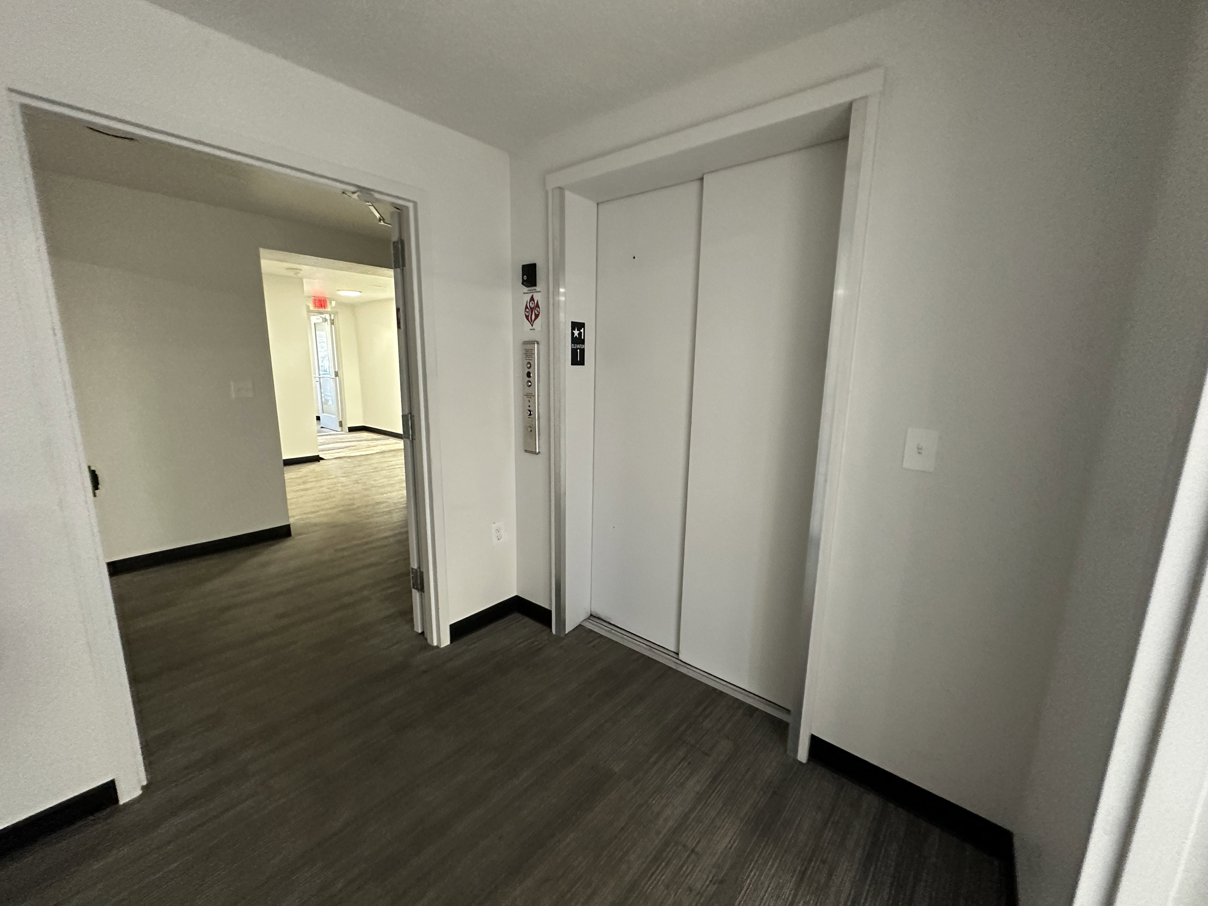 Hallway with dark wood finished floors and elevator