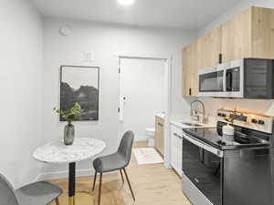 Kitchen featuring appliances with stainless steel finishes, light brown cabinetry, light wood-style flooring, and light countertops