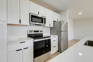 Kitchen featuring appliances with stainless steel finishes, light countertops, light wood-style flooring, white cabinetry, and recessed lighting