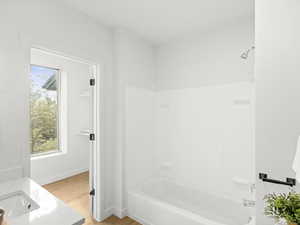 Full bath featuring bathing tub / shower combination, wood finished floors, and vanity