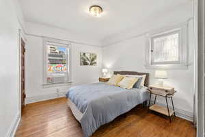 Bedroom with wood finished floors and cooling unit