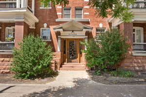 Doorway to property with brick siding, cooling unit, and a balcony