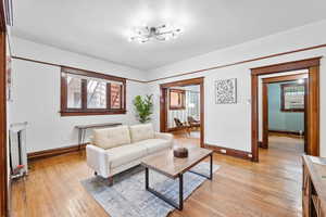 Living room with light wood-style flooring, a chandelier, and cooling unit