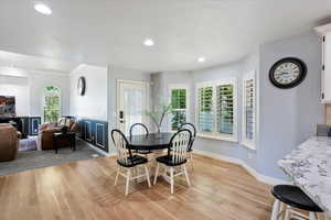 Dining space with light wood-style flooring, recessed lighting, ornamental molding, and a wainscoted wall