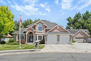 Traditional-style home with an attached garage, driveway, stucco siding, roof with shingles, and brick siding