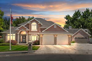 View of front of property featuring a garage, concrete driveway, stucco siding, and brick siding