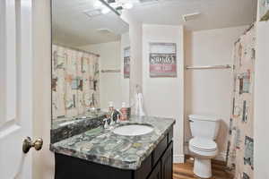Full bath featuring vanity, wood finished floors, and a textured ceiling